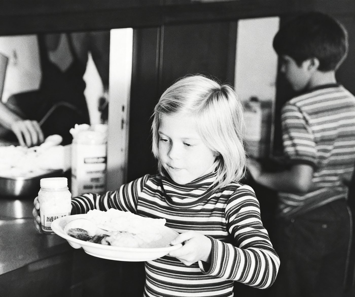 A young student carries her lunch tray
