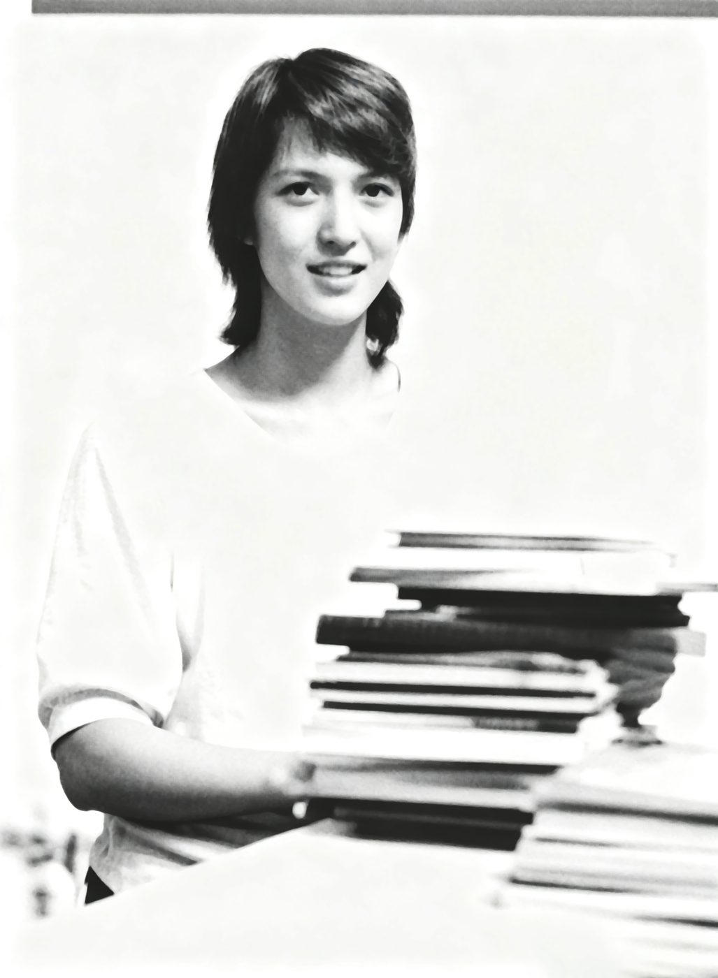 A student carrying a tall stack of books