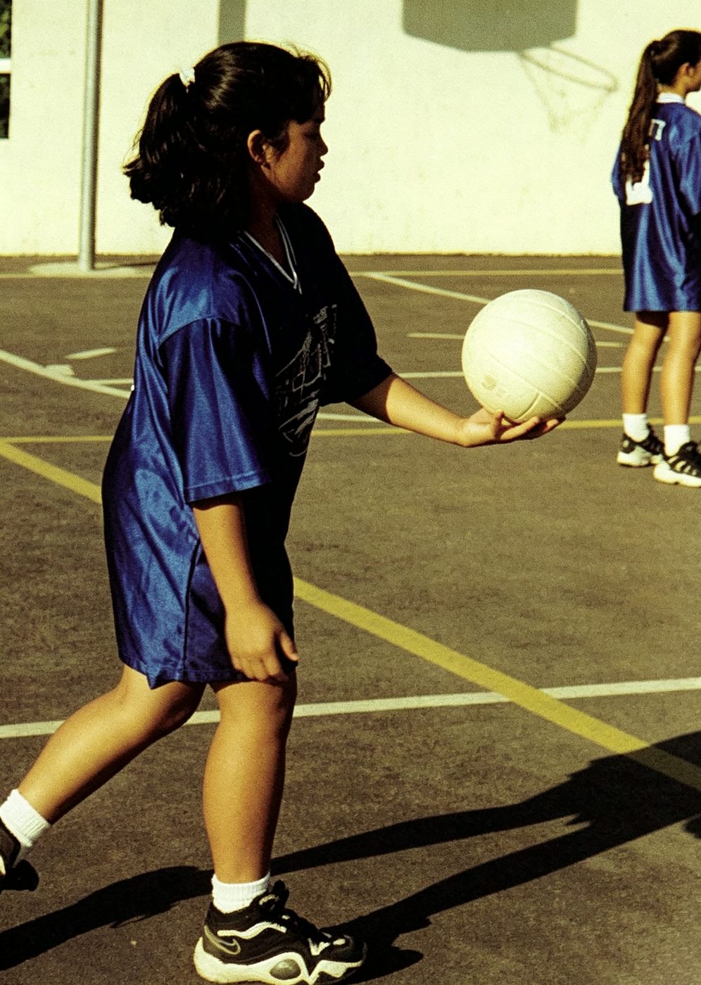 A student serves a volleyball on the school court