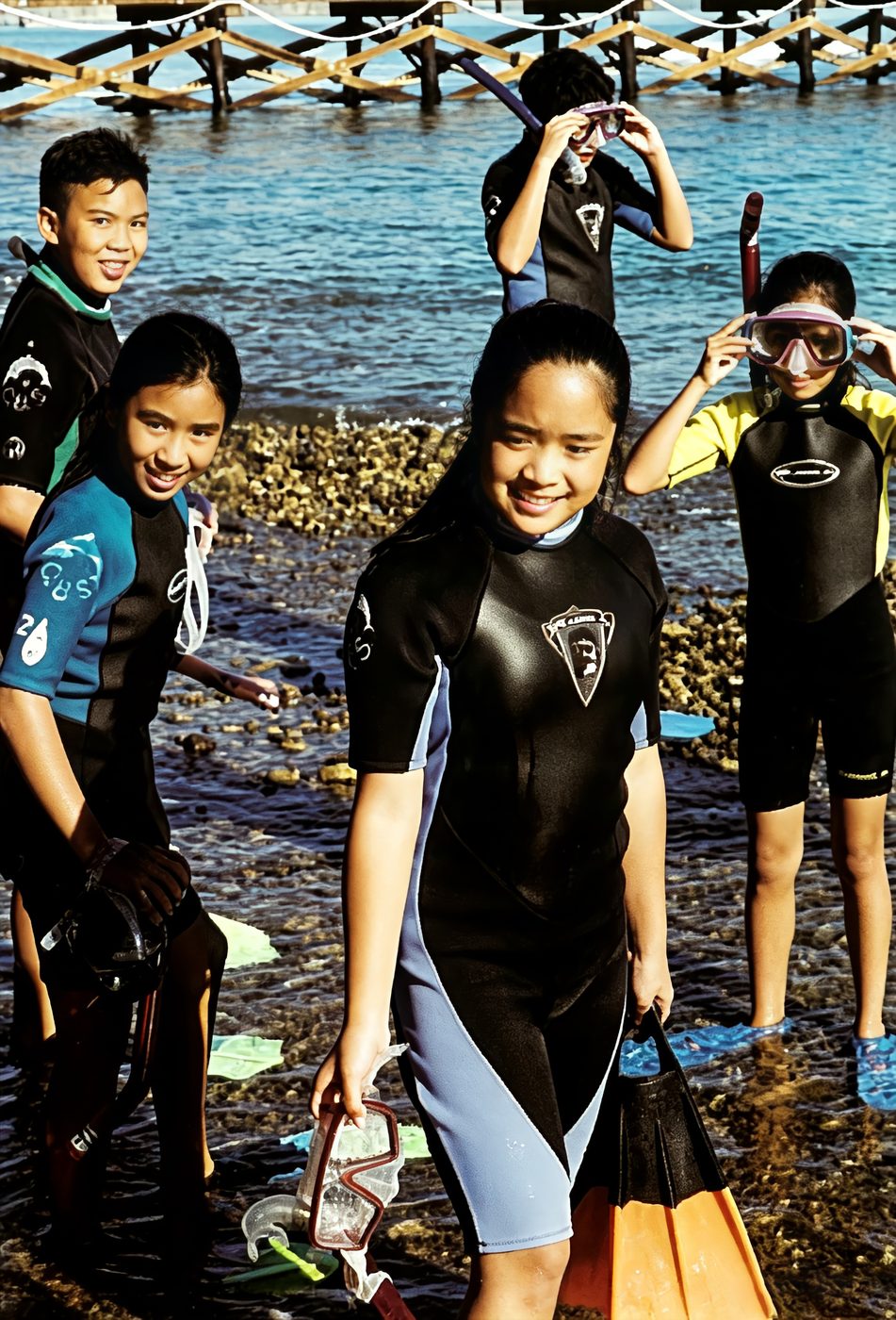 Students in wetsuits with snorkels on an ocean field trip